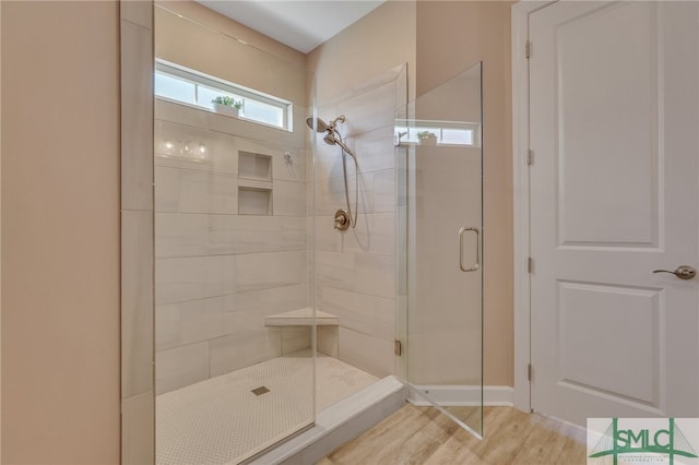 bathroom with hardwood / wood-style floors and a shower with shower door