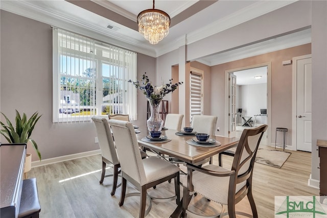 dining room featuring an inviting chandelier, light hardwood / wood-style flooring, and ornamental molding