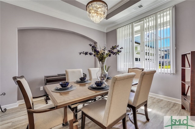 dining space with light wood-type flooring, a notable chandelier, and crown molding