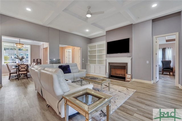 living room featuring beamed ceiling, coffered ceiling, ceiling fan with notable chandelier, and light wood-type flooring