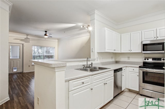 kitchen with sink, kitchen peninsula, appliances with stainless steel finishes, crown molding, and light wood-type flooring