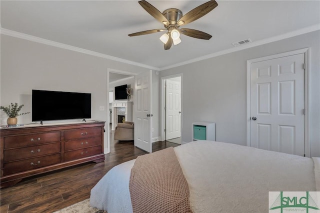 bedroom with ceiling fan, a fireplace, dark wood-type flooring, and ornamental molding