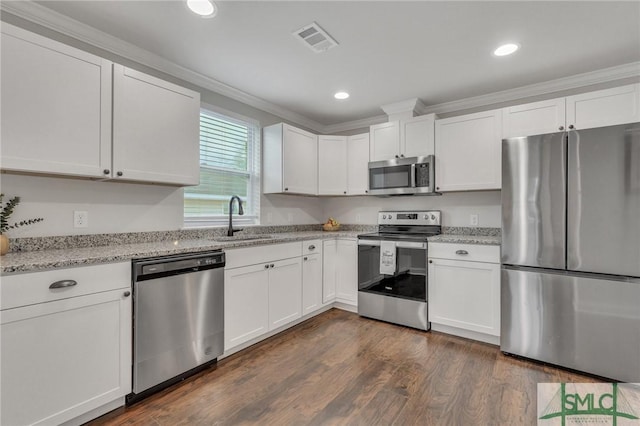 kitchen with light stone countertops, appliances with stainless steel finishes, dark hardwood / wood-style flooring, sink, and white cabinetry