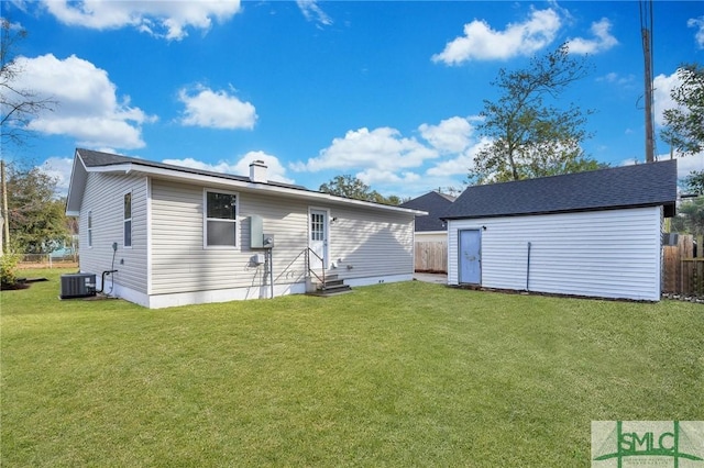 back of house featuring central AC, an outdoor structure, and a lawn