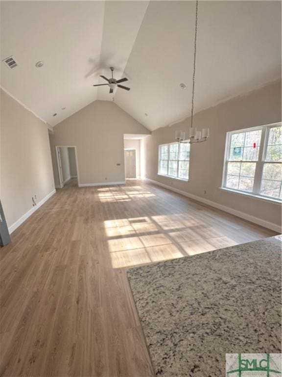 unfurnished living room with hardwood / wood-style floors, ceiling fan with notable chandelier, and lofted ceiling