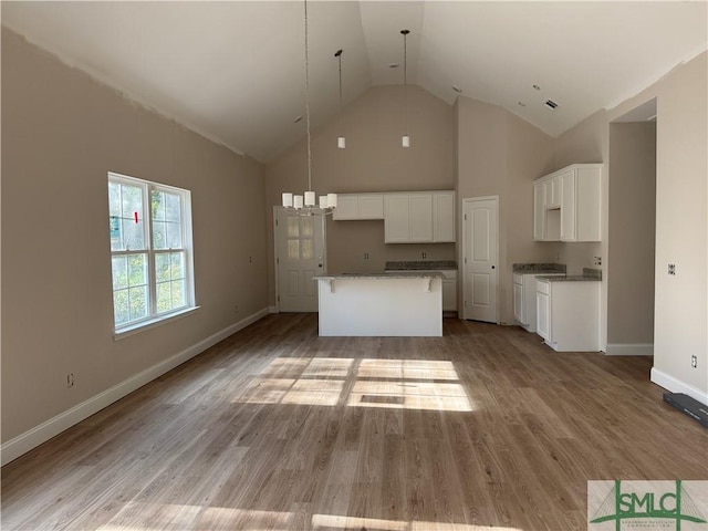 kitchen featuring a kitchen island, white cabinetry, high vaulted ceiling, and light hardwood / wood-style flooring