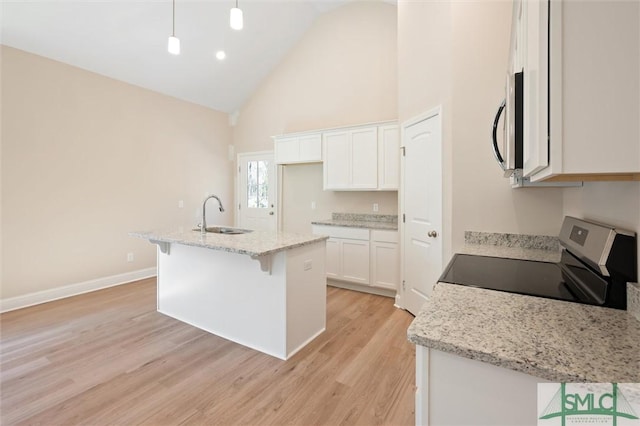 kitchen featuring a center island with sink, stainless steel appliances, light wood-style flooring, white cabinetry, and a sink