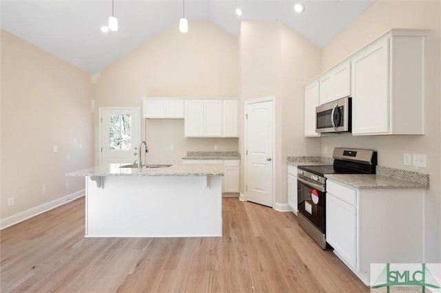 kitchen with a sink, white cabinetry, appliances with stainless steel finishes, light wood finished floors, and an island with sink