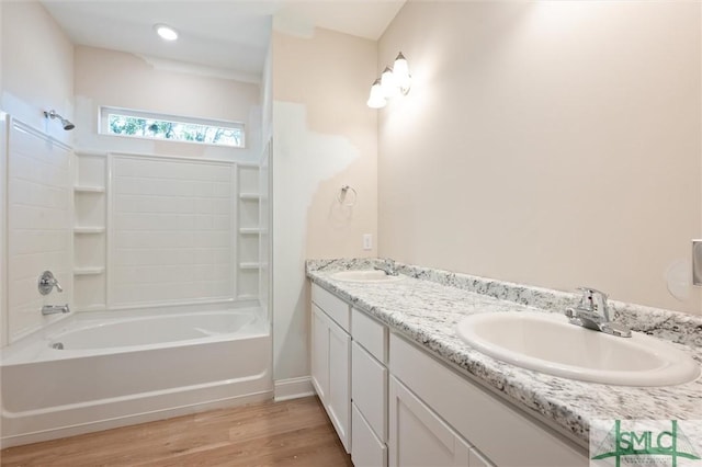 bathroom with double vanity, wood finished floors, a sink, and washtub / shower combination