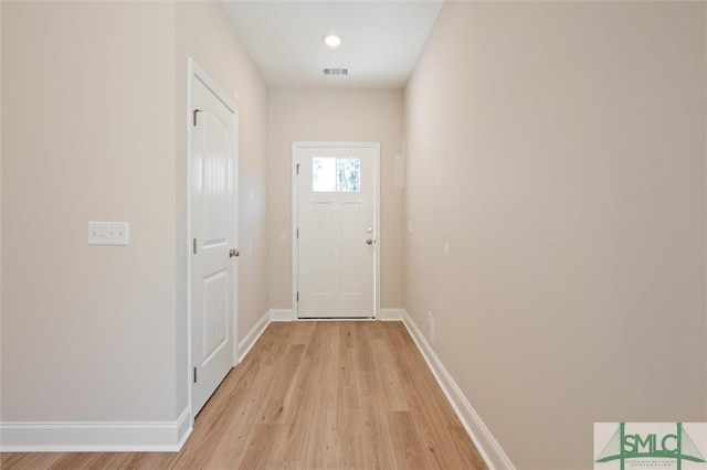 doorway featuring light wood-style flooring, visible vents, and baseboards