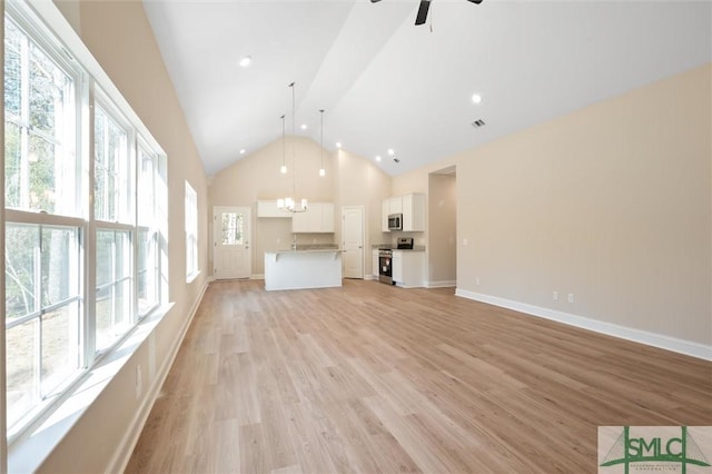 unfurnished living room with high vaulted ceiling, light wood-style flooring, ceiling fan with notable chandelier, visible vents, and baseboards