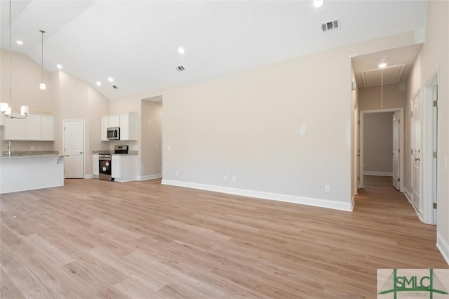 unfurnished living room featuring attic access, visible vents, light wood-style floors, and high vaulted ceiling