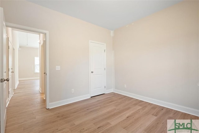 unfurnished bedroom featuring baseboards, attic access, and light wood-style floors