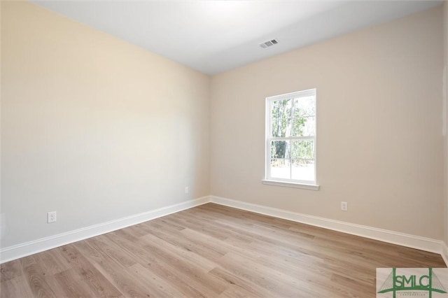 empty room featuring light wood-style floors, visible vents, and baseboards