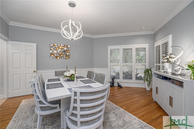 dining area with light wood-type flooring, a notable chandelier, and crown molding