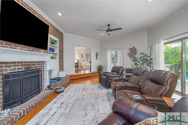 living room with a brick fireplace, wood-type flooring, plenty of natural light, and ornamental molding