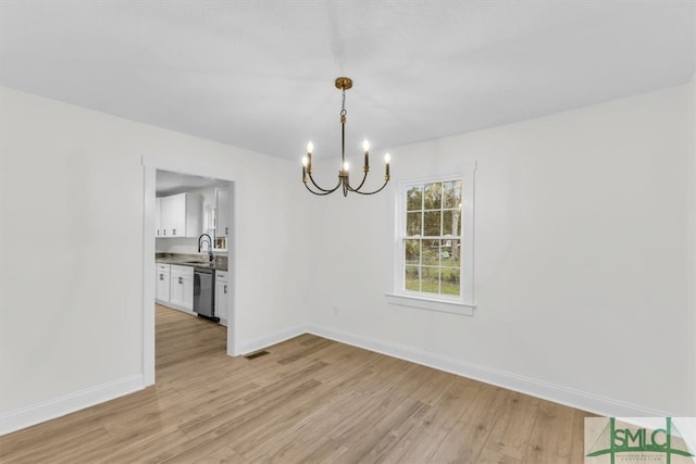 unfurnished dining area with light wood-type flooring, a notable chandelier, and sink