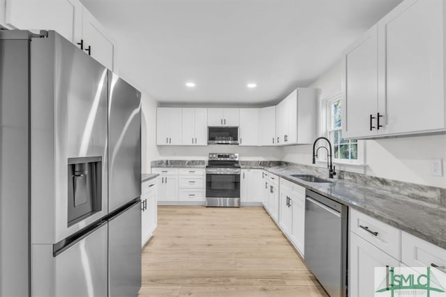 kitchen with white cabinetry, appliances with stainless steel finishes, sink, and light hardwood / wood-style flooring