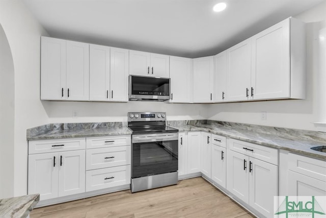 kitchen with white cabinetry, appliances with stainless steel finishes, light stone countertops, and light wood-type flooring