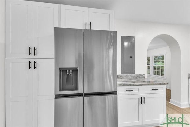 kitchen featuring white cabinets, light stone countertops, stainless steel fridge with ice dispenser, and electric panel