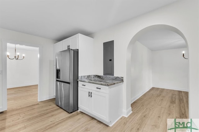 kitchen with electric panel, light hardwood / wood-style floors, dark stone counters, white cabinetry, and stainless steel fridge