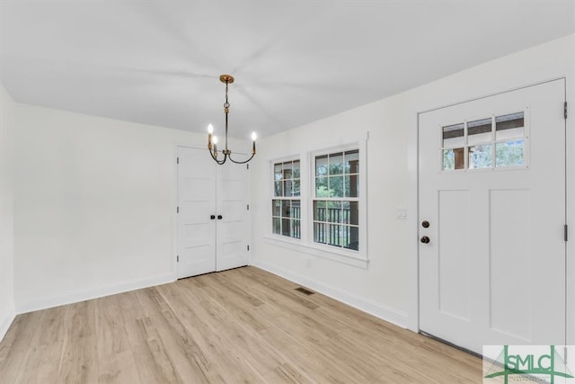 foyer featuring a wealth of natural light, an inviting chandelier, and light wood-type flooring