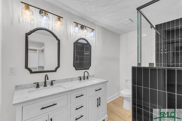 bathroom with hardwood / wood-style flooring, a textured ceiling, vanity, a shower, and toilet