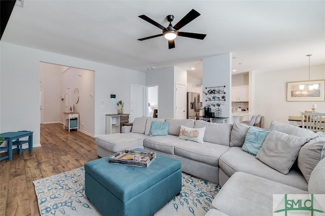 living room with ceiling fan with notable chandelier and light hardwood / wood-style floors