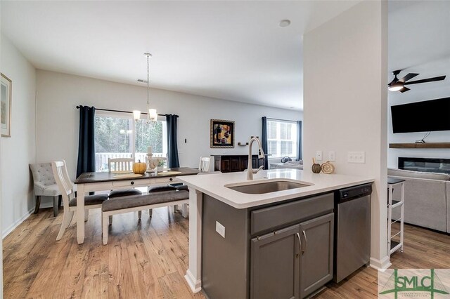 kitchen featuring pendant lighting, sink, gray cabinets, light hardwood / wood-style flooring, and stainless steel dishwasher