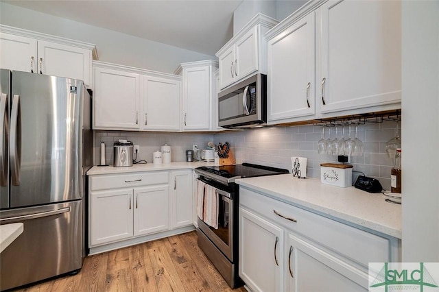 kitchen with tasteful backsplash, stainless steel appliances, light wood-type flooring, and white cabinets