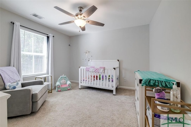 carpeted bedroom with a nursery area and ceiling fan