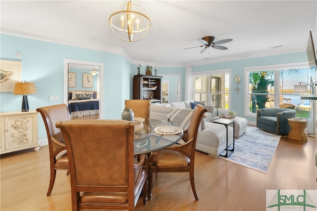 dining space featuring ceiling fan with notable chandelier, light wood-type flooring, and crown molding