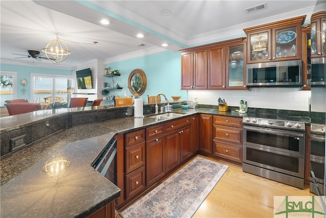 kitchen with crown molding, sink, hanging light fixtures, light wood-type flooring, and stainless steel appliances