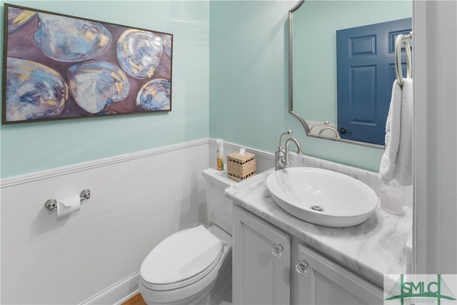 bathroom with vanity, toilet, and tile walls