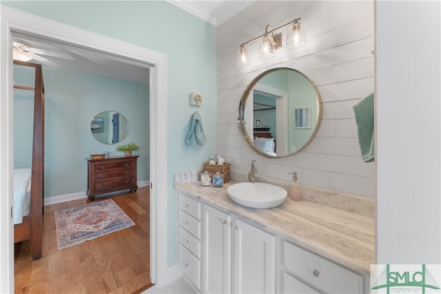 bathroom with hardwood / wood-style flooring, vanity, ceiling fan, and crown molding