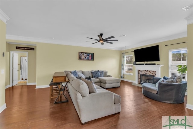 living room featuring dark wood-type flooring, a fireplace, ceiling fan, and ornamental molding