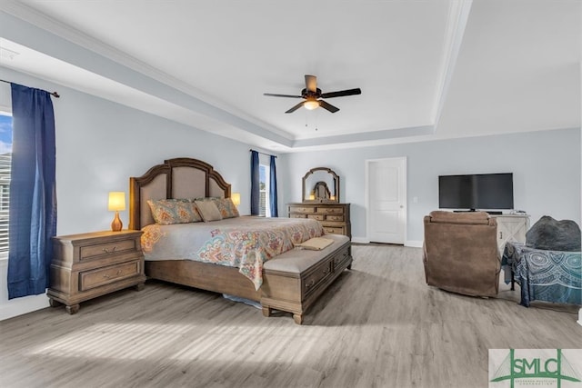 bedroom with light wood-type flooring, ceiling fan, and a raised ceiling