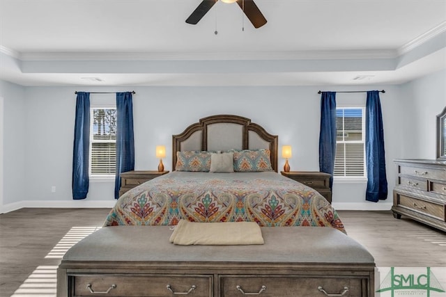 bedroom with ornamental molding, a tray ceiling, hardwood / wood-style flooring, and ceiling fan