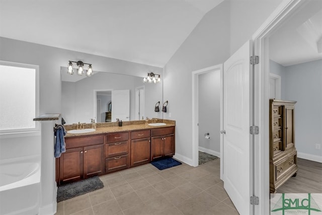 bathroom with tile patterned floors, vanity, a bathing tub, and lofted ceiling