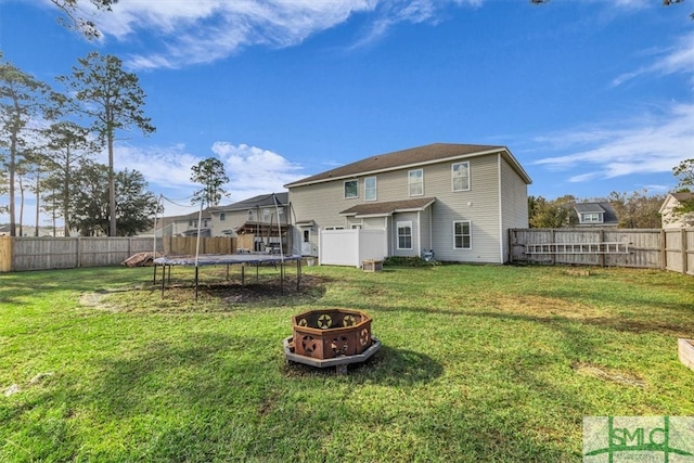 rear view of house featuring a yard and a trampoline