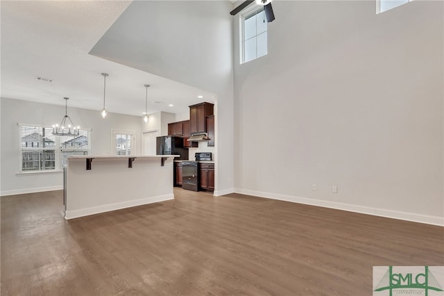 kitchen with black appliances, dark hardwood / wood-style flooring, hanging light fixtures, and a kitchen breakfast bar