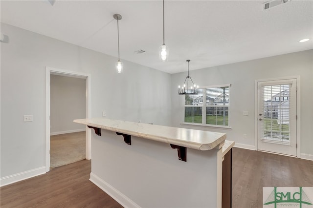 kitchen featuring a chandelier, decorative light fixtures, a kitchen breakfast bar, and dark hardwood / wood-style floors