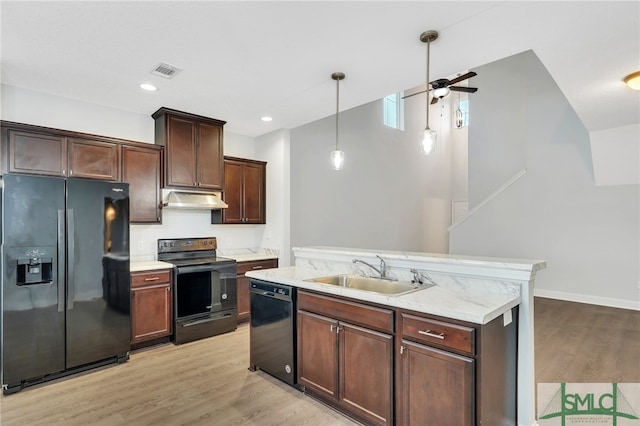 kitchen with dark brown cabinetry, hanging light fixtures, black appliances, sink, and light wood-type flooring