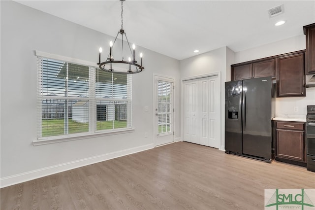 kitchen featuring fridge with ice dispenser, dark brown cabinetry, pendant lighting, a chandelier, and light hardwood / wood-style flooring