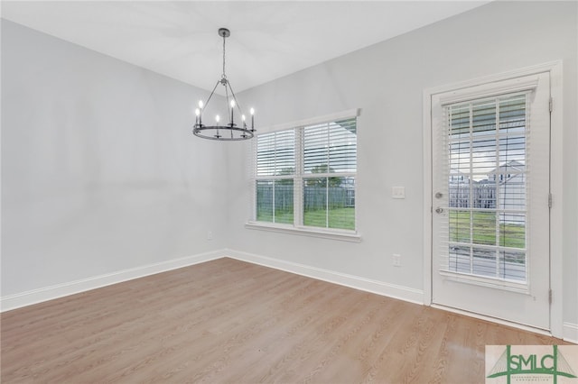 unfurnished dining area featuring a chandelier, a wealth of natural light, and light hardwood / wood-style floors