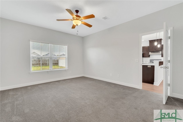 carpeted spare room featuring ceiling fan