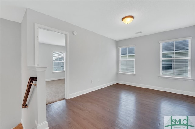 unfurnished room featuring dark wood-type flooring and plenty of natural light