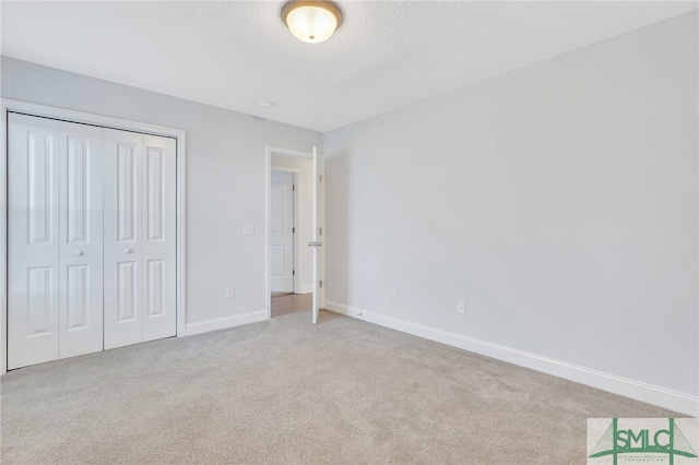 unfurnished bedroom with light colored carpet and a closet