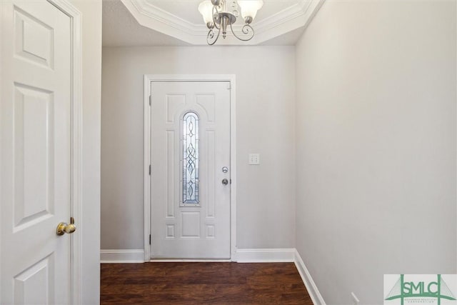 entrance foyer featuring a raised ceiling, dark hardwood / wood-style flooring, crown molding, and a notable chandelier