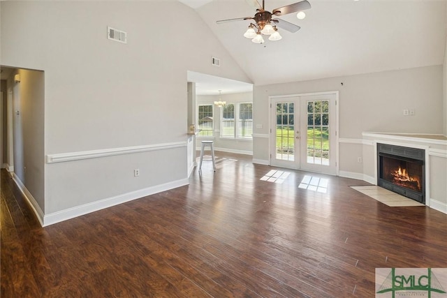 unfurnished living room featuring hardwood / wood-style floors, ceiling fan with notable chandelier, high vaulted ceiling, and french doors